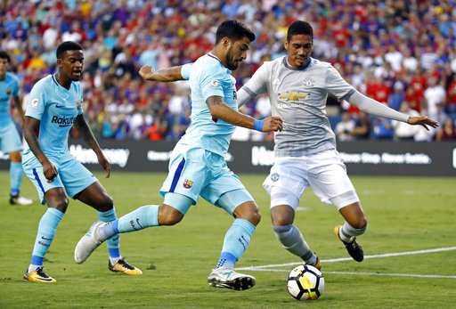 Hậu vệ Smalling (phải) ngăn chặn Suarez trong trận đấu giữa MU và Barcelona tại Mỹ